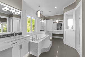 Bathroom with crown molding, tile patterned floors, a garden tub, two vanities, and baseboards