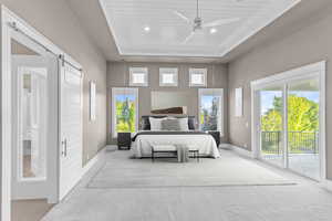 Bedroom with a barn door, access to exterior, wood ceiling, carpet floors, and a tray ceiling
