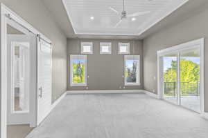 Empty room featuring a barn door, baseboards, ceiling fan, and healthy amount of natural light