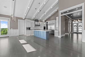 Kitchen featuring white cabinetry, beam ceiling, light countertops, backsplash, and pendant lighting