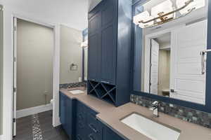 Bathroom with toilet, decorative backsplash, double vanity, baseboards, and tile patterned flooring
