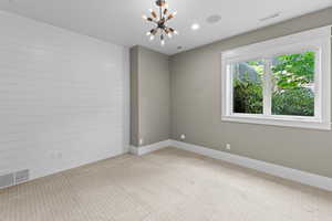 Carpeted empty room with baseboards and a chandelier