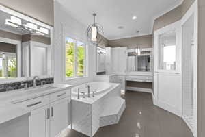 Full bath with ornamental molding, a garden tub, two vanities, and recessed lighting