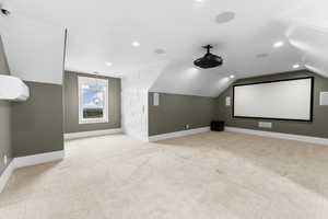 Home theater room with light carpet, lofted ceiling, and recessed lighting