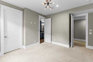 Unfurnished bedroom featuring a chandelier and light colored carpet