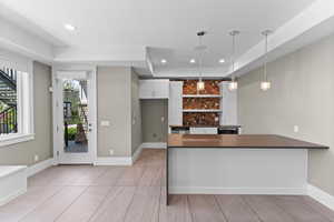 Kitchen featuring dark countertops, decorative light fixtures, white cabinets, a peninsula, and recessed lighting