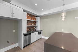Bar area featuring appliances with stainless steel finishes, a sink, baseboards, light tile patterned floors, and recessed lighting