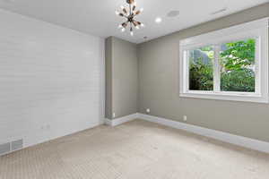 Unfurnished room featuring a chandelier, light colored carpet, baseboards, and recessed lighting