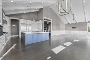 Kitchen with a sink, open floor plan, beamed ceiling, blue cabinetry, and high vaulted ceiling