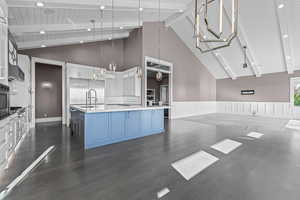 Kitchen with white cabinetry, dark wood-style floors, a large island, open floor plan, and high vaulted ceiling