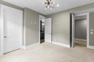 Unfurnished bedroom featuring carpet floors, a chandelier, and baseboards