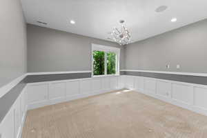 Spare room featuring a decorative wall, a wainscoted wall, light colored carpet, a chandelier, and recessed lighting