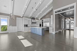 Kitchen with built in appliances, light countertops, dark wood-style flooring, white cabinetry, and high vaulted ceiling