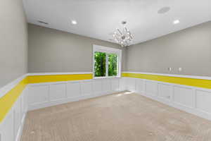 Unfurnished room featuring carpet floors, wainscoting, a chandelier, recessed lighting, and a decorative wall
