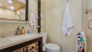 Full bath with a tile shower, toilet, and vanity