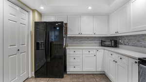 Kitchen featuring black appliances, white cabinetry, light countertops, recessed lighting, and light tile patterned flooring