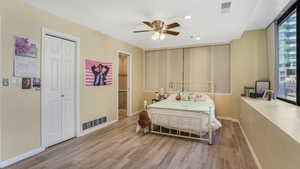 Bedroom with wood finished floors, baseboards, recessed lighting, a closet, and ensuite bath