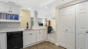 Kitchen featuring dishwasher, a sink, white cabinets, light countertops, and recessed lighting