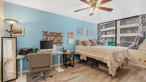 Bedroom featuring wood finished floors, baseboards, a desk, and ceiling fan