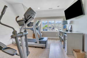 Workout area with light wood-style floors, baseboards, and recessed lighting