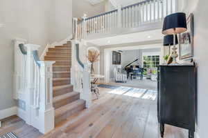 Foyer entrance with wood-type flooring, a high ceiling, stairway, and baseboards