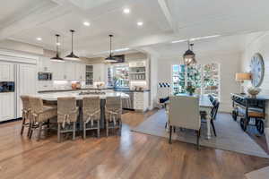 Kitchen featuring open shelves, built in appliances, wood finished floors, white cabinetry, and backsplash