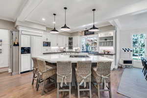Kitchen featuring built in appliances, ornamental molding, open shelves, wood finished floors, and white cabinetry