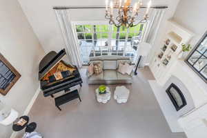 Living area featuring a chandelier, built in features, baseboards, and a high ceiling