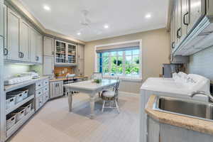 Kitchen featuring washer and clothes dryer, wallpapered walls, ornamental molding, light countertops, and a ceiling fan