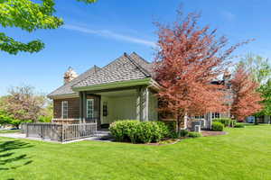 Rear view of property featuring a yard, a chimney, central AC, and a deck