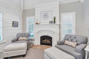 Carpeted living room featuring wooden walls and a glass covered fireplace