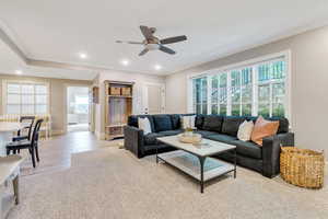 Living area with healthy amount of natural light, a ceiling fan, crown molding, recessed lighting, and baseboards