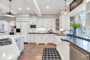 Kitchen featuring built in appliances, a sink, crown molding, backsplash, and white cabinets