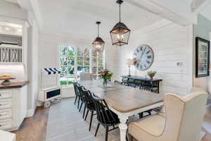 Dining space with a chandelier, wood finished floors, wooden walls, and ornamental molding