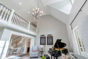 Living area with high vaulted ceiling, arched walkways, a chandelier, baseboards, and recessed lighting