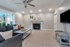 Living room with ceiling fan, a fireplace with flush hearth, ornamental molding, recessed lighting, and baseboards