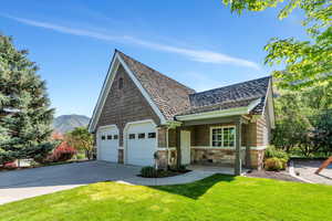 View of front of property featuring stone siding, a front yard, driveway, and a mountain view