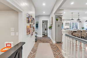 Hallway with baseboards, brick flooring, and recessed lighting