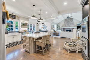 Kitchen with a ceiling fan, a sink, appliances with stainless steel finishes, light wood-type flooring, and a center island