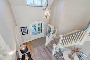 Entryway featuring a high ceiling, french doors, stairs, a chandelier, and wood finished floors