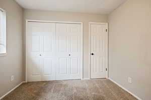 Unfurnished bedroom with carpet, baseboards, and a closet