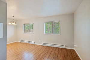 Empty room with a baseboard radiator, wood finished floors, and baseboards
