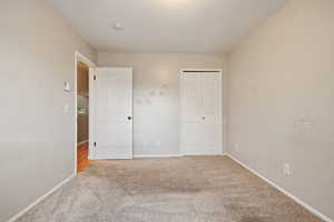 Unfurnished bedroom featuring carpet floors, baseboards, and a closet