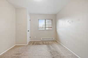 Unfurnished room with baseboard heating, carpet, and baseboards
