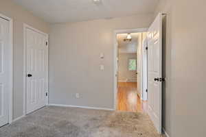 Unfurnished bedroom featuring a baseboard heating unit, light colored carpet, baseboards, and a textured ceiling