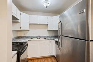 Kitchen featuring stainless steel appliances, a sink, light wood-style flooring, light countertops, and white cabinets