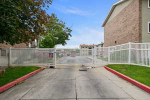 View of concrete road with a gate, curbs, and a gated entry