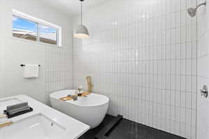 Owners Suite: Full bathroom with tile walls, a freestanding tub, tiled shower, and a sink