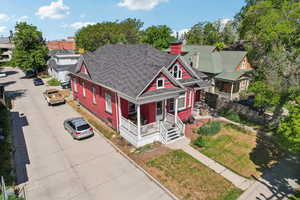 View of front of home with covered porch, a chimney, and roof with shingles