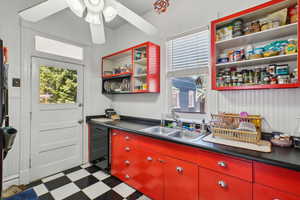 Kitchen featuring red cabinetry, open shelves, tile patterned floors, and black dishwasher